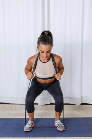 Woman doing a squat using resistant band