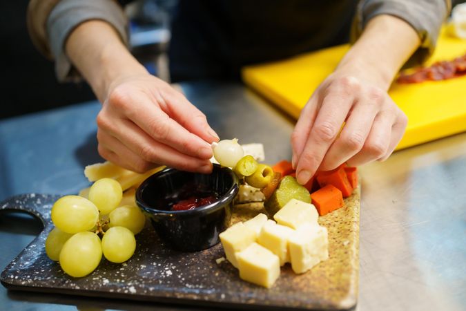 Person plating a cheese board
