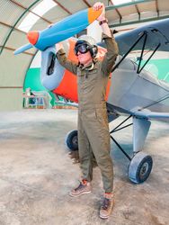 Confident pilot beside retro plane in hangar