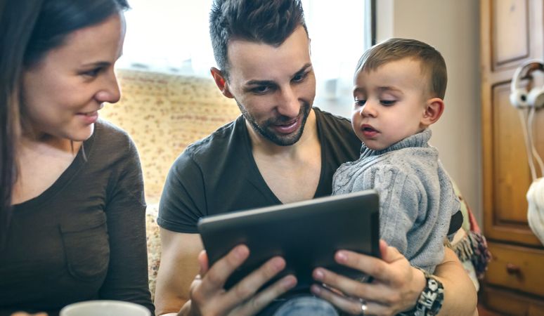 Family with child and pregnant mother looking tablet