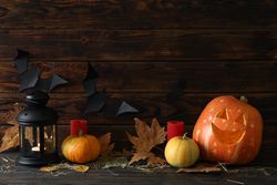 Halloween pumpkins and candles on dark wooden background, copy space