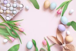 Top view of Easter eggs, tulips and paper bag with copy space