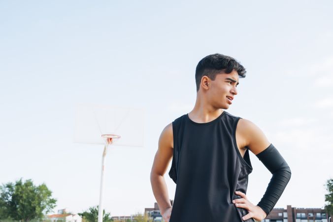 Young man playing on basketball court outdoor.