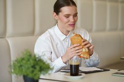 Smiling businesswoman eating a sandwich in a modern coffee shop