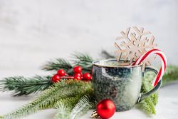 Mug of hot drink with candy cane and decorative pine