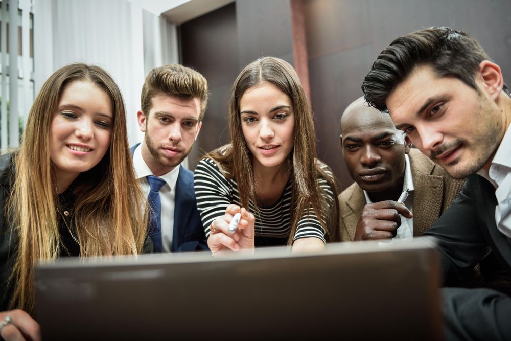Male and female colleagues gathered around a laptop