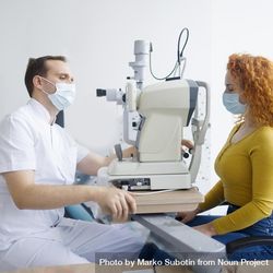 Side view of optometrist looking into patient’s eyes with equipment 5Qr9g4