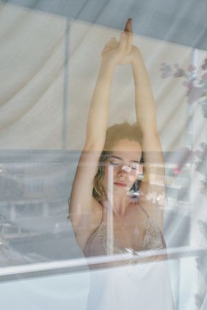 Serene woman stretching in morning near window