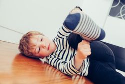Cute blonde boy putting on his socks