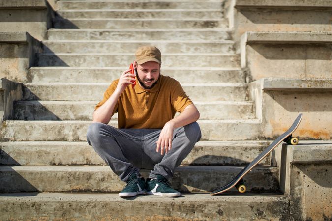 a young man talking on the phone while sitting on some steps