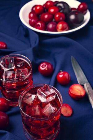 Red beverage near fresh fruits on cloth