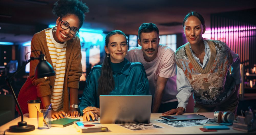 Posing Shot of a Diverse Group of Talented Young Business People Gathered Around a Desk in a Modern Creative Office, Brainstorming. Smiling