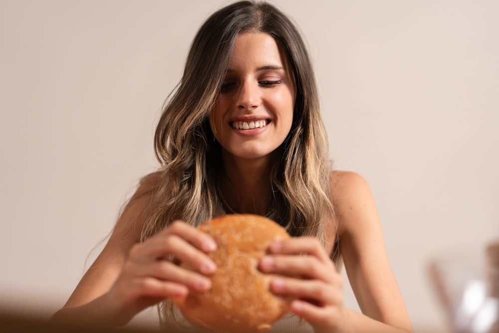 Young woman enjoying burger happy smile food pleasure lifestyle mindful eating balance wellness joy