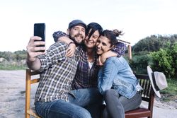 A group of friends sitting outdoors and taking a selfie