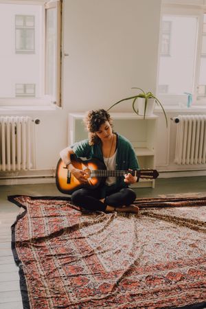 Content woman playing guitar at home