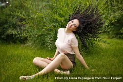Teenage girl flicking her dark curly hair while sitting in the grass 56X8lb