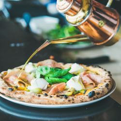 Olive oil being poured on freshly made wood oven baked pizza