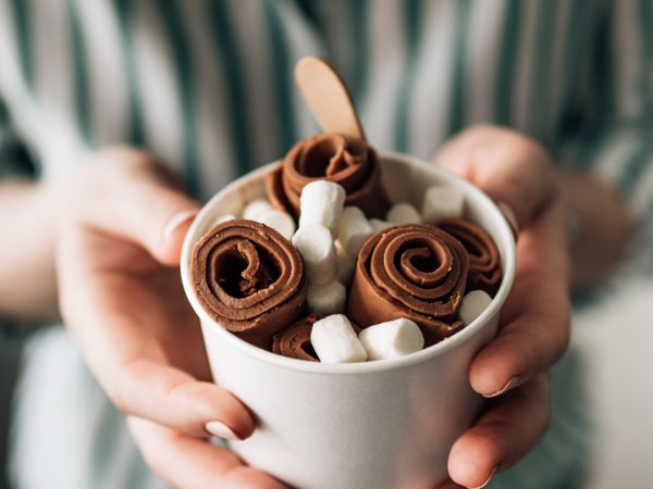 Hand holding rolled ice cream in cone cup