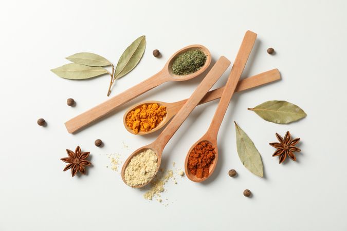 Top view of scattered wooden spoons full of colorful earth tone spices