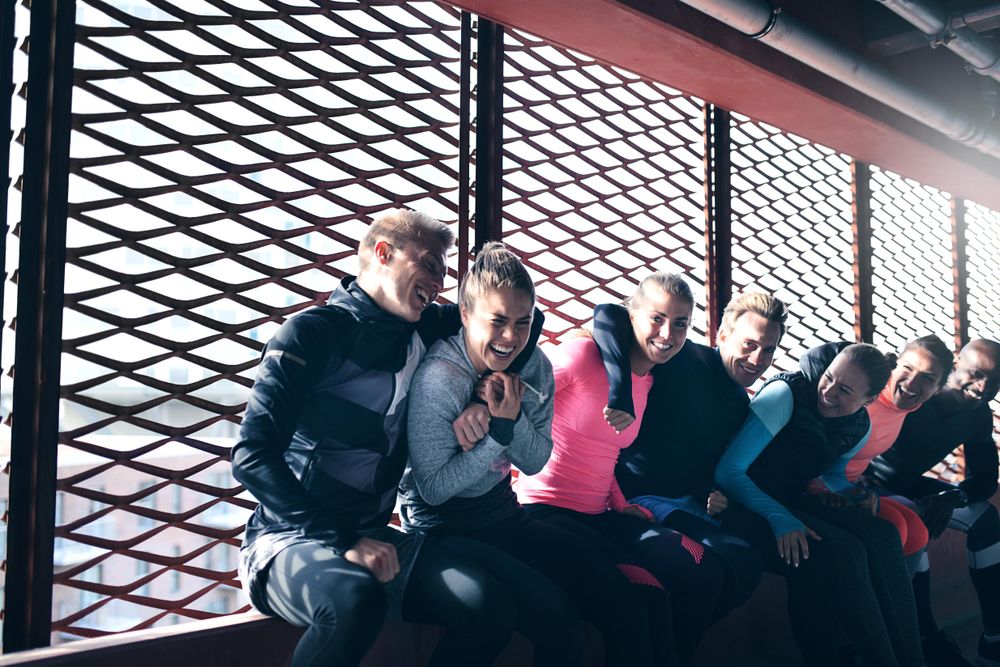 Happy athletic people sitting on window ledge