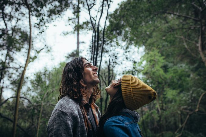 Young couple looking up and smiling in forest