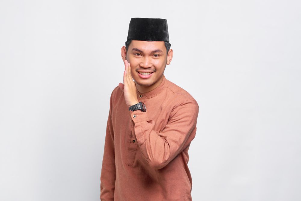 Muslim man in kufi head wear telling a secret
