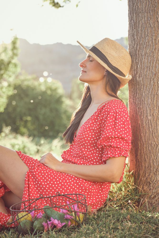 Smiling woman in summer dress sitting on grass