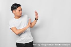 Asian male in grey studio gesturing “no” with both hands with copy space bYBXd0