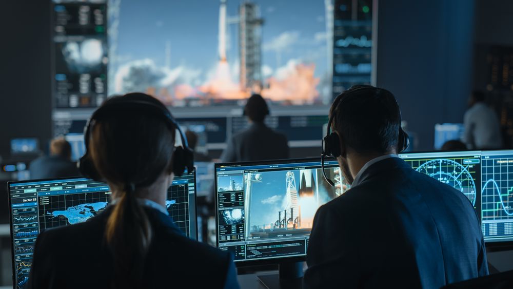 Mission Control Team Monitors Rocket Launch. Technicians With Headsets Analyze Data on Screens.