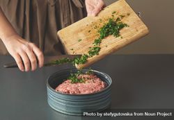 Woman mixing parsley into ground beef 4ZdWy0