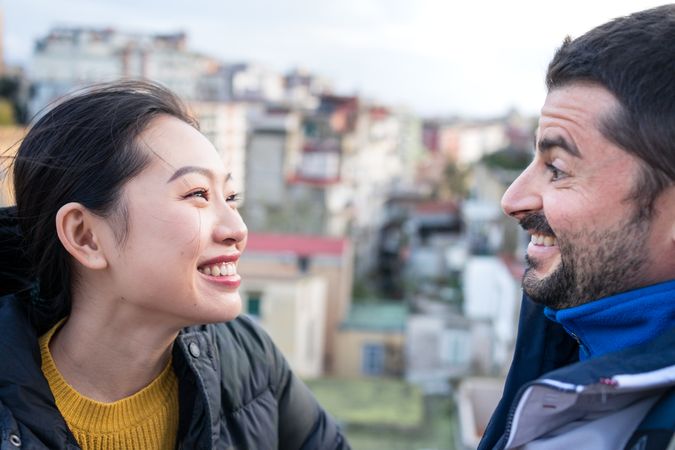 Positive multiethnic resting couple talking while walking at city street