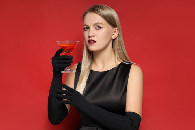 A woman at a party in the style of Halloween with a cocktail in her hands