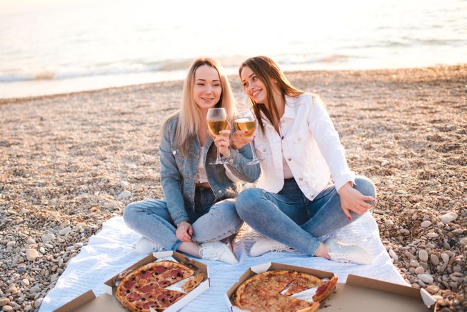 Two women enjoying pizzas and wine at the beach