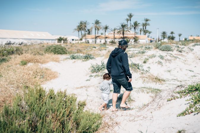 Man with kid walking along sandy hills