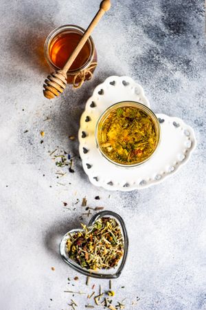Top view of floral tea in glass with honey pot and dipper on grey counter