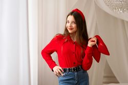 Smiling teen girl posing with red high heels indoors.