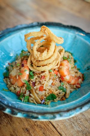 Bowl of delicious fried rice with shrimps on wooden table