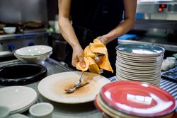 Crop woman cleaning cutleries and plates in kitchen