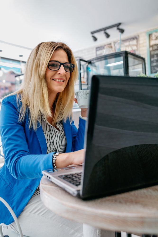 Woman drinking coffee and working with the laptop