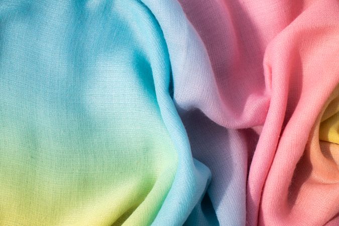 Gradient yellow blue pink and green fabric wavy spiral crumpled background texture with copy space.