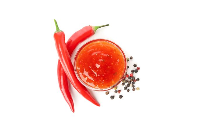 Chilli pepper and bowl of sauce isolated on plain background