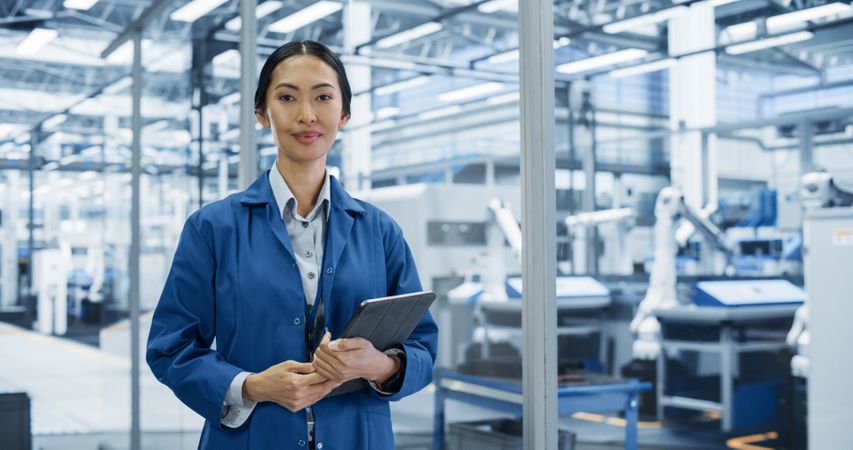 Portrait of Electronics Manufacture Engineer Smiling, Posing for Camera. Happy Asian Female Working at a Production Plant with Artificial Intelligence Robotic Systems
