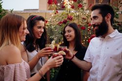 Group of cheerful friends clinking glasses at party