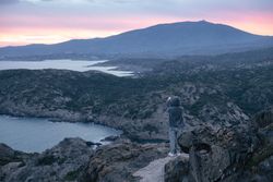 Solo traveller taking photo on cliff at sunset
