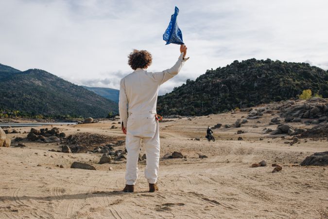 Rear view of man in jumpsuit waving blue flag at motorcycle