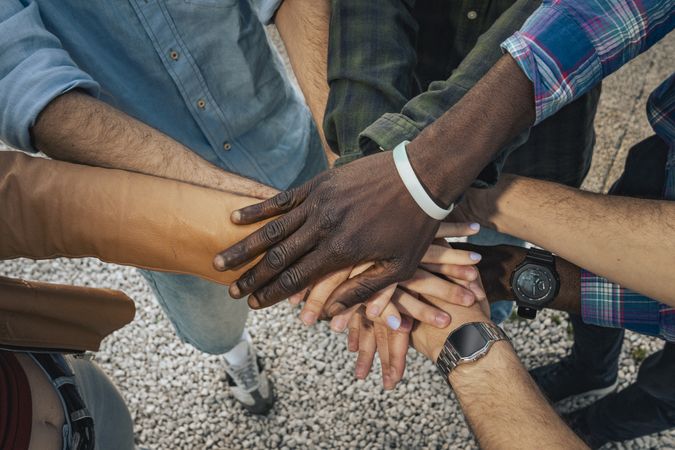 Diverse group teamwork joining hands outdoors in unity and support