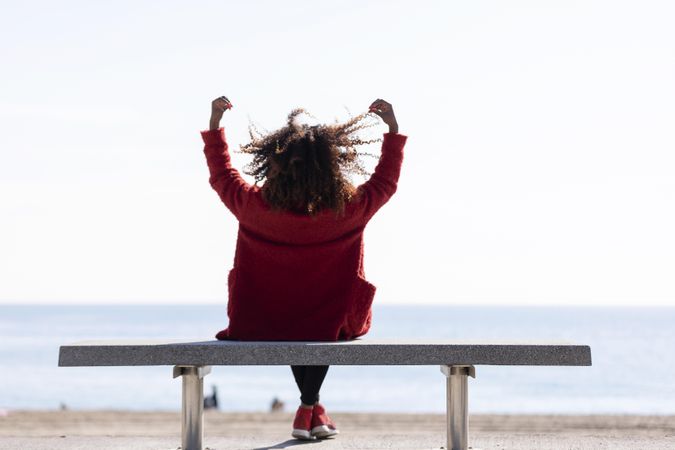 Back of woman celebrating something while over looking the ocean