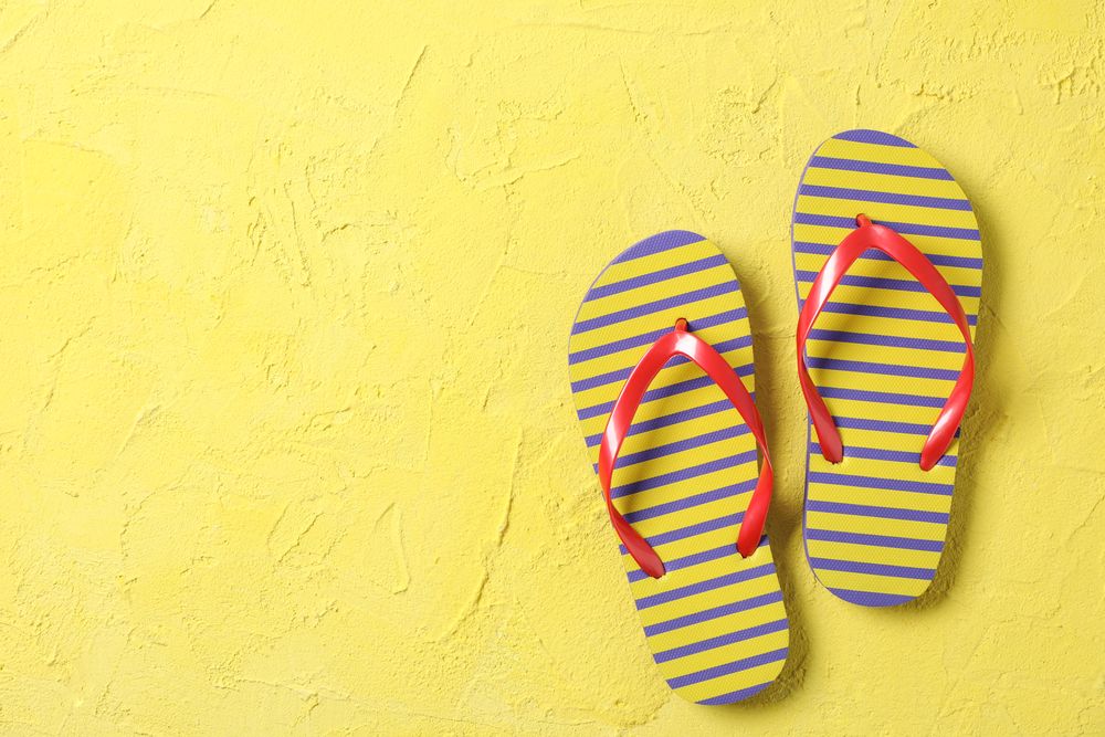 Flip flops on color background, space for text and top view. Summer vacation backdrop