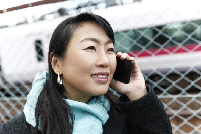Woman wearing blue scarf having a phone call outdoor