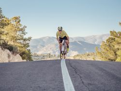 healthy man riding a bicycle on a mountain road in a sunny day